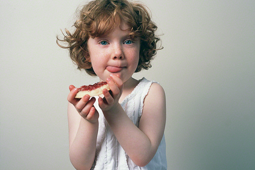 open portrait of little girl staring at camera eating