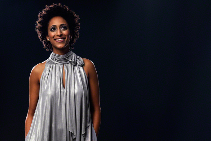 in studio portrait of a beautiful black woman against dark background, glamourous, glimmering 
