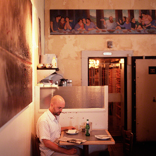 guy sitting at table reading in a warmly lit restaurant, The Nose, Toronto, editorial assignment for the New York Times