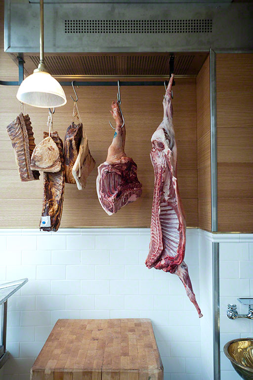 photo of a variety of meat hanging in a small butcher shop, cote de beuf, toronto