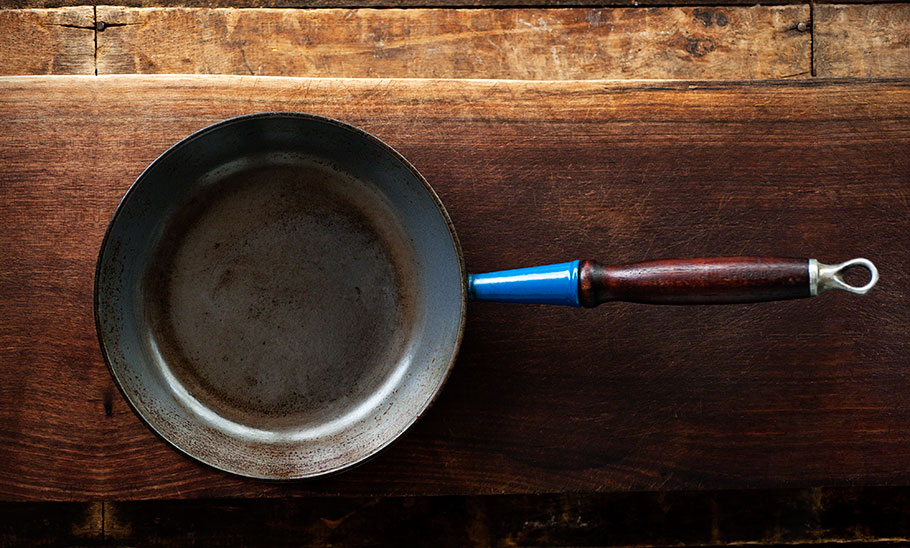 overhead shot of a well used cast iron frying pan on a wooden table