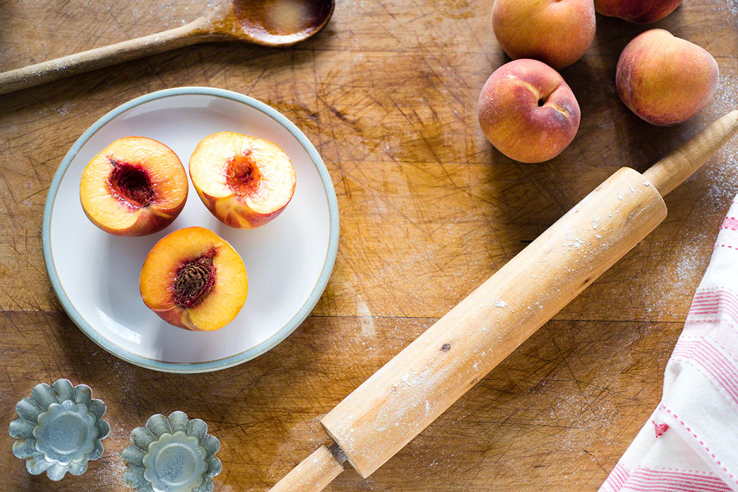 editorial, overhead shot of a splice of life, baking peach tarts scene, natural light, food