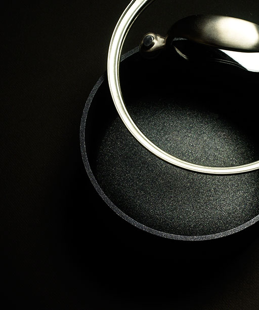 overhead shot of black saucepan with glass lid on black background, product photography, housewares