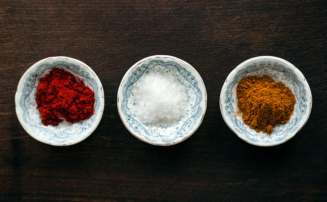 overhead shot of 3 fresh bowls of spices on a wooden background