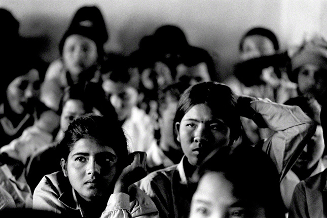 nepal, focus is on 2 girls looking intently in all girl classroom