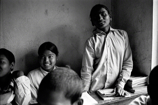 teenage nepalese girl stands at desk in classroom setting