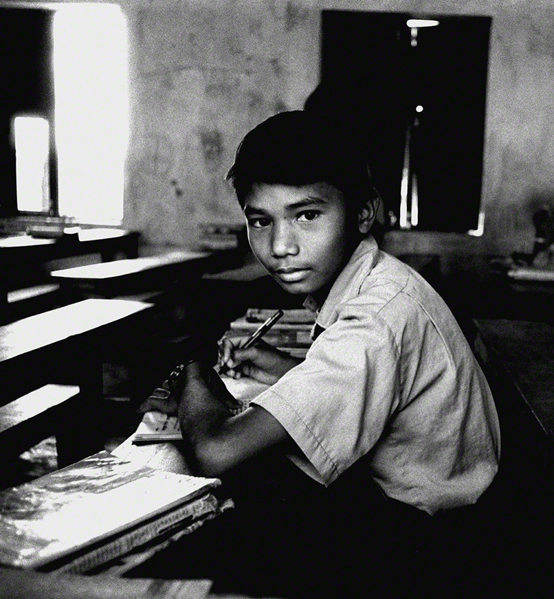 middle school aged nepalese boy studying at his desk 