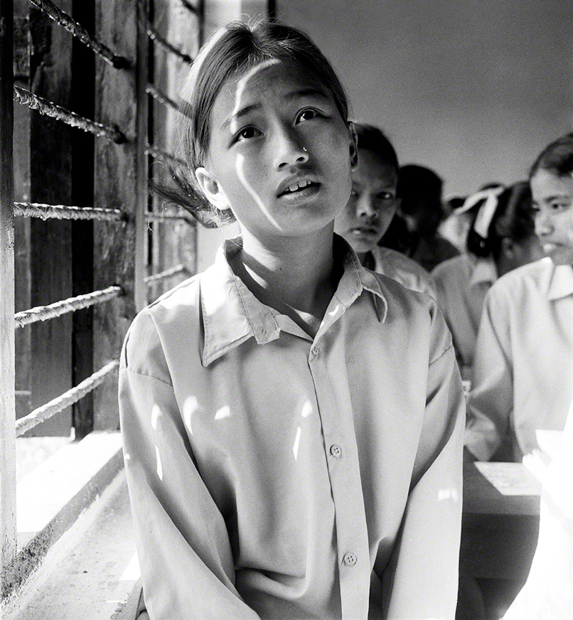 young female, nepalese student sitting next to window in classroom