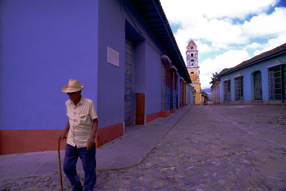 old man walking with cane with San Fransisco de Asis bellow tower in background Trinidad de Cuba
