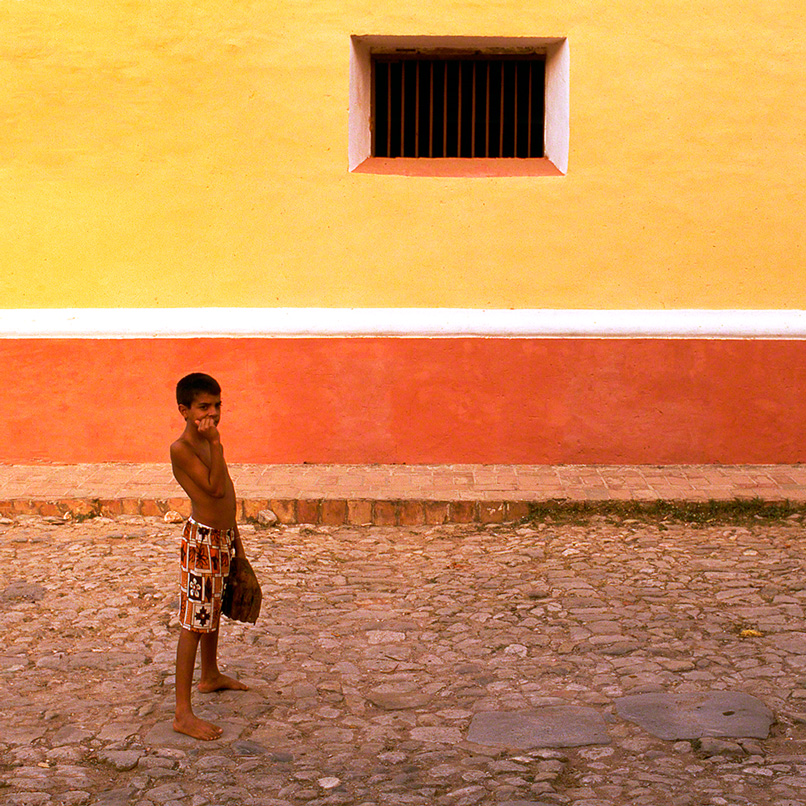 boy playing baseball in the colorful streets of Trinidad de Cuba