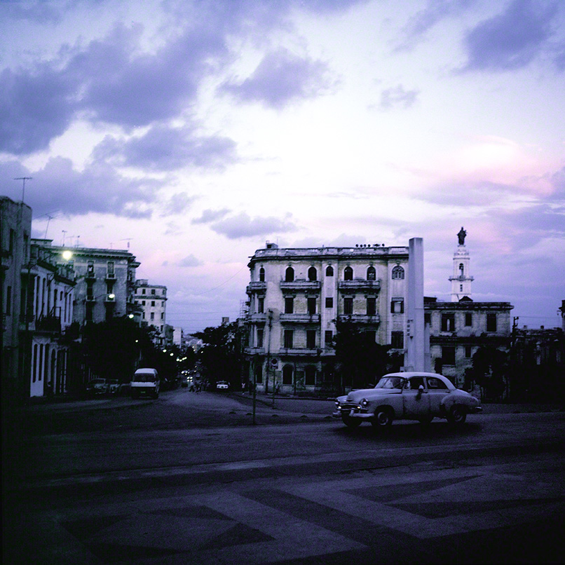 lone car moving thru frame in Havana university plaza at sunset
