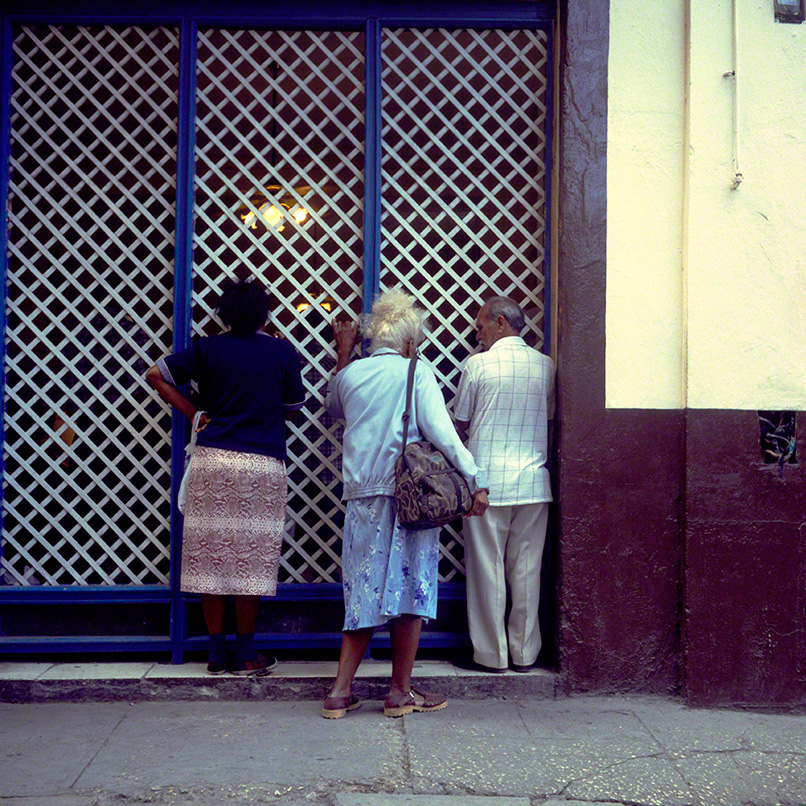 Cubans peering thru front window of store front