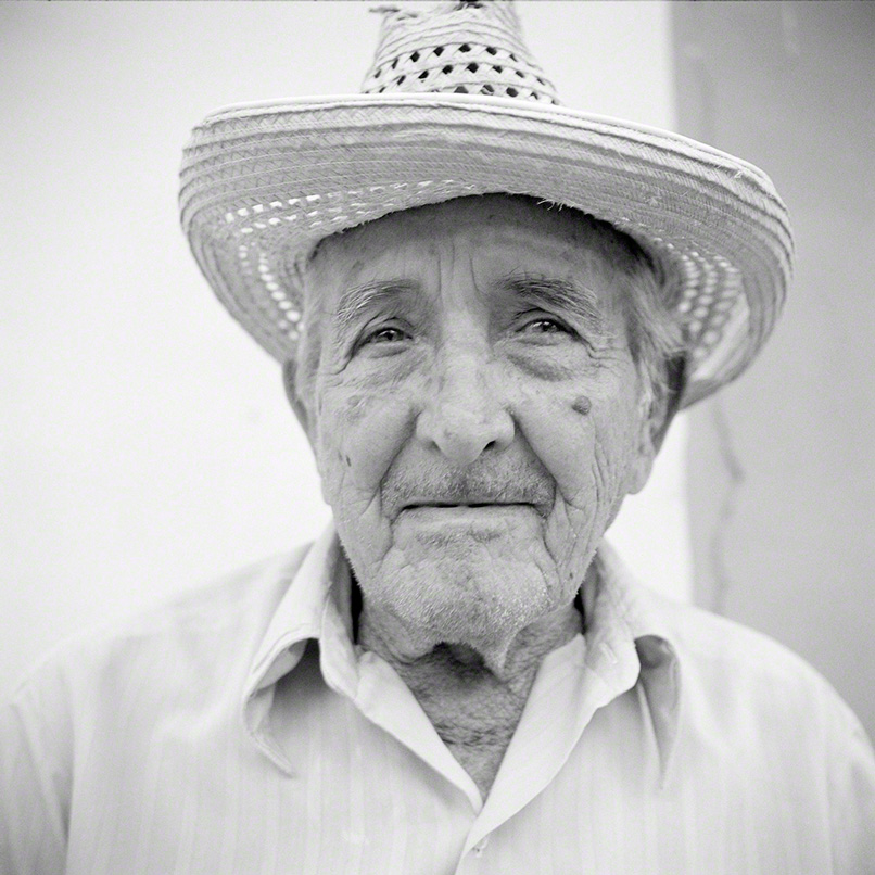 black and white closeup portrait of old man wearing a straw hat