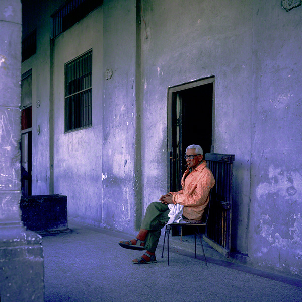 old man sits by his front door in Havana